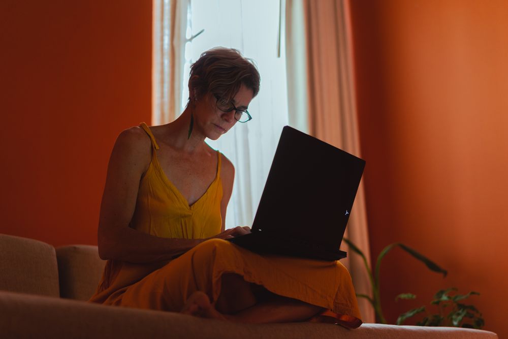An older woman using her laptop in a comfortable room at home