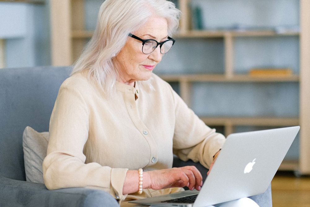 An older woman confidently using her laptop at home